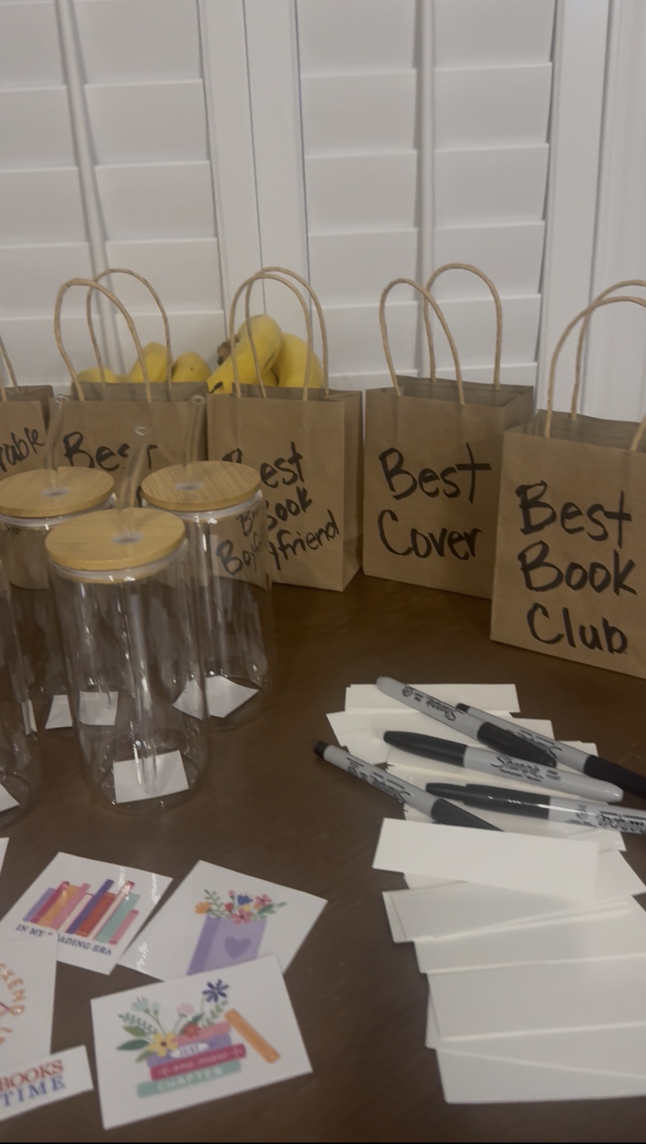 Kraft paper award bags labeled Best Cover and Best Book Boyfriend, next to glass cups, markers, and bookish stickers ready for crafting